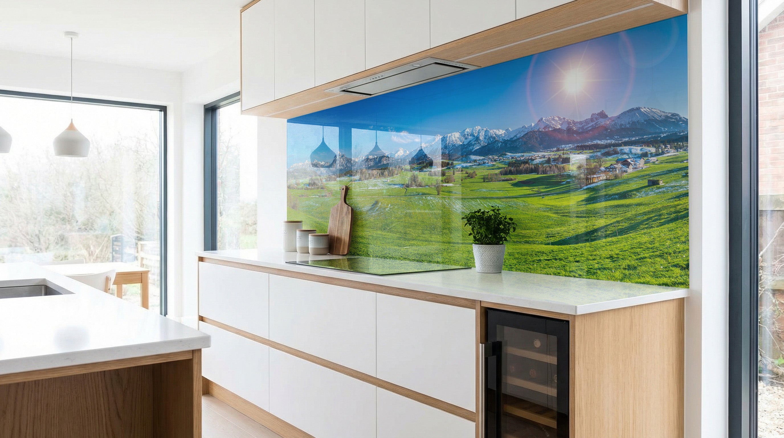 Moderne Küche mit weißen Schränken und einer Küchenrückwand „Sonnenaufgang Alpenwiesen“ von glasposter.com.