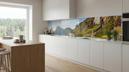 Moderne Küche mit weißen Schränken, einer Kücheninsel aus Holz und einer Küchenrückwand mit Alpenpanorama von glasposter.com.