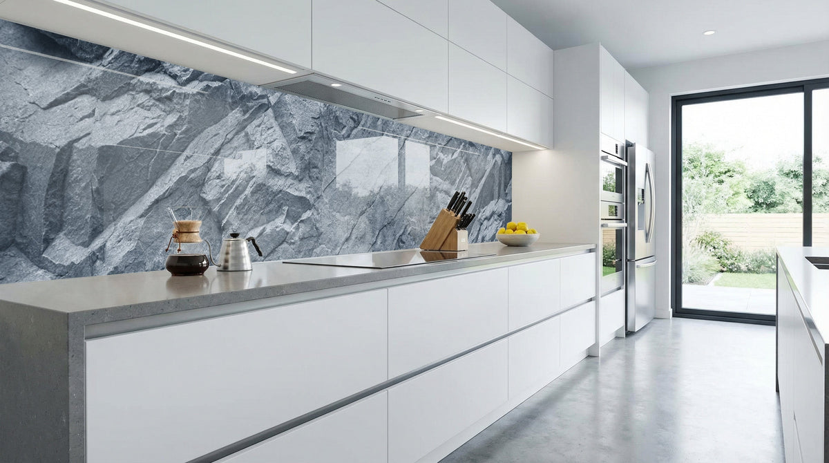 Moderne Küche mit weißen Schränken, einer Küchenrückwand „Felswand Granit Grau“ von glasposter.com und einem großen Fenster.