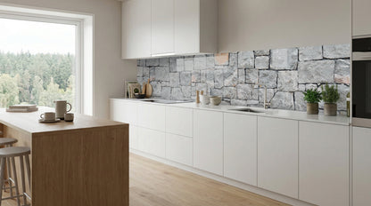 Moderne weiße Küche mit Kücheninsel aus Holz, Blick ins Waldgebiet und einer Rückwand aus grauem Naturstein von glasposter.com.
