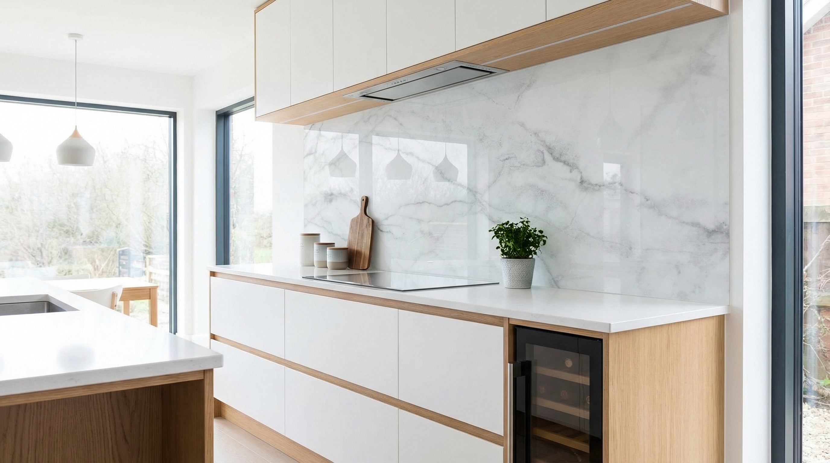 Moderne Küche mit weißen Schränken, Holzakzenten und einer Küchenrückwand von glasposter.com in der Ausführung „Marmor Weiß Grau Adern“.