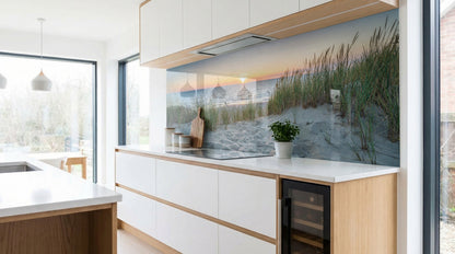 Moderne Küche mit weißen Schränken und einer Küchenrückwand von glasposter.com mit dem Motiv „Dünenlandschaft Sonnenuntergang“.