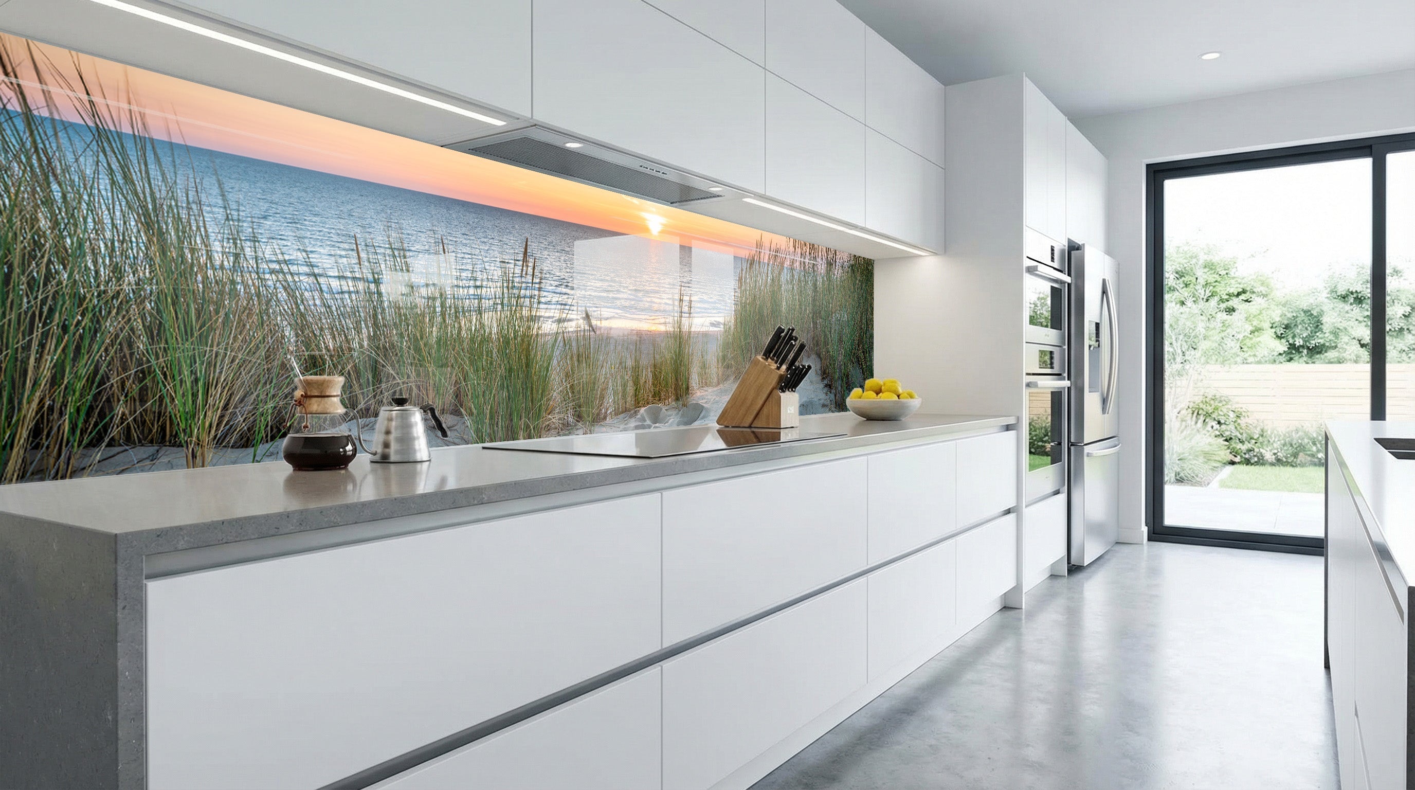 Moderne Küche mit einer Küchenrückwand „Dünenlandschaft Sonnenuntergang“ von glasposter.com und weißen Schränken.