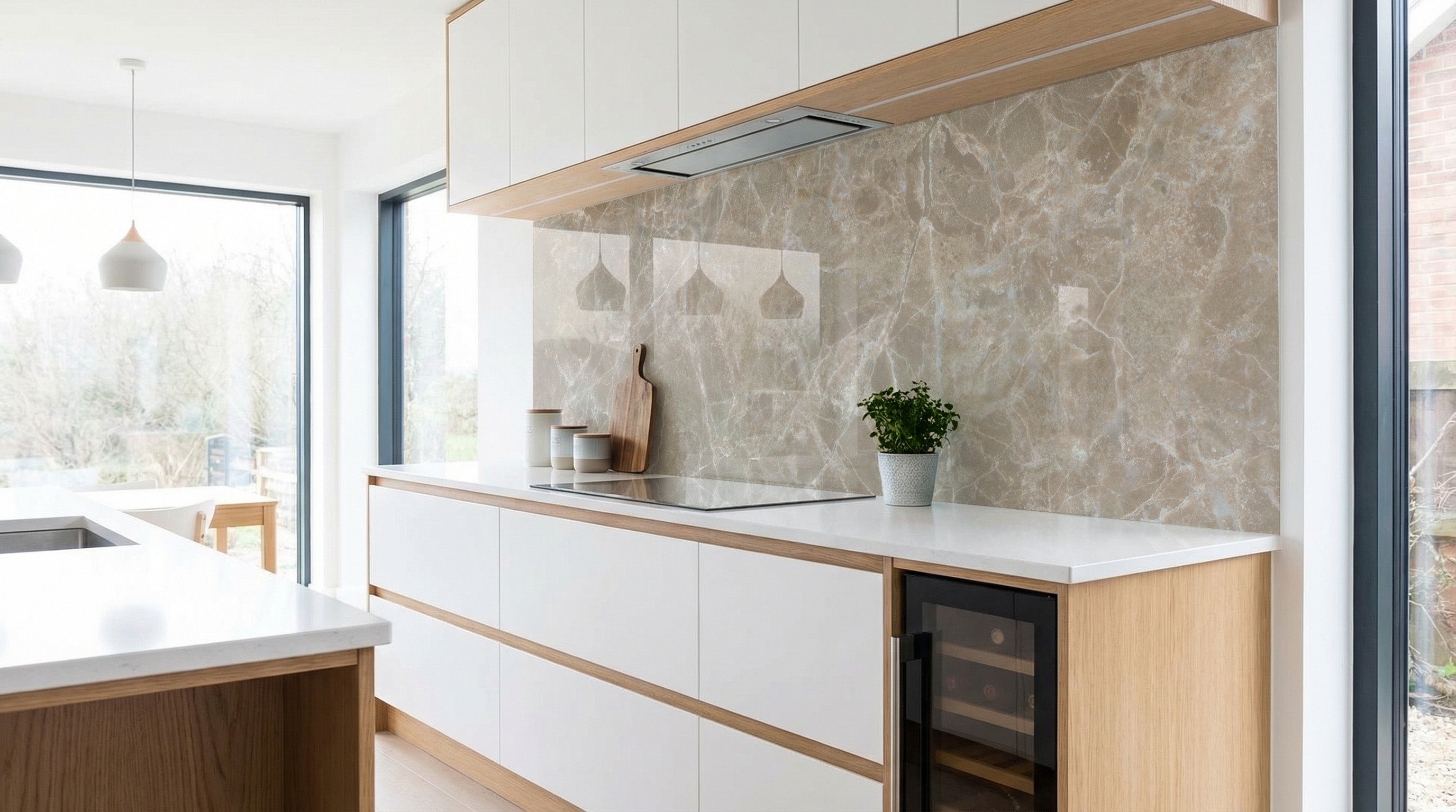 Moderne Küche mit weißen Schränken, Küchenrückwand – Marmor Hellbeige-Grau von glasposter.com – und einer Pflanze.