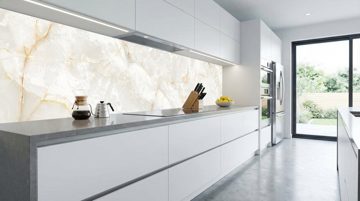 Moderne Küche mit weißen Schränken, einer Küchenrückwand aus Calacatta-Gold-Marmor von glasposter.com und einem großen Fenster.