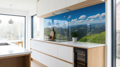Moderne Küche mit weißen Schränken und einer Küchenrückwand „Berglandschaft blauer Himmel“ von glasposter.com.