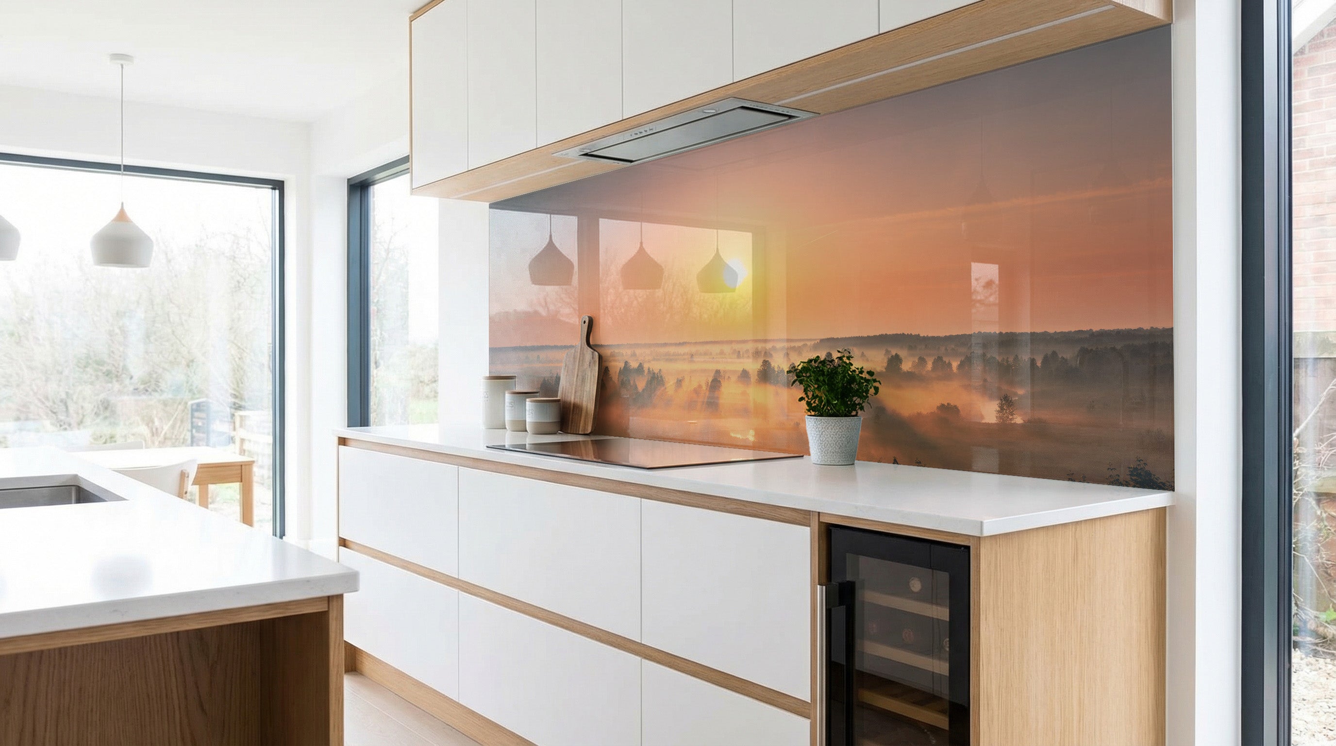 Moderne Küche mit weißen Schränken, Holzakzenten und einer Rückwand von glasposter.com mit dem Motiv „Nebelfeld – Sonnenaufgang“.