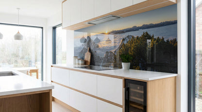 Moderne Küche mit weißen Schränken und einer Küchenrückwand – „Sonnenuntergang Bergsee Wald“ von glasposter.com.