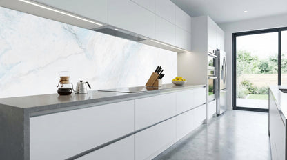 Moderne weiße Küche mit einer Küchenrückwand aus weiß-blauem Marmor von glasposter.com, einem Messerblock und Blick in den Garten.