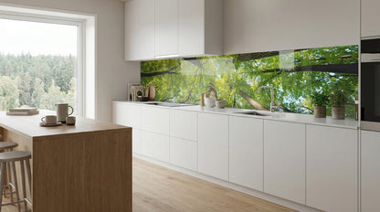 Moderne weiße Küche mit Holzakzenten, ausgestattet mit einer Küchenrückwand „Blick in die Baumkronen“ von glasposter.com.